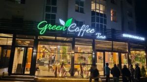 Exterior of Green Coffee Time restaurant in Ifrane city at night, showing the modern glass facade and cozy seating.
