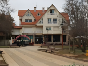 Exterior view of For You Restaurant in Ifrane, Morocco, featuring traditional alpine architecture with a red-tiled sloped roof and a neon sign in a park-like setting.