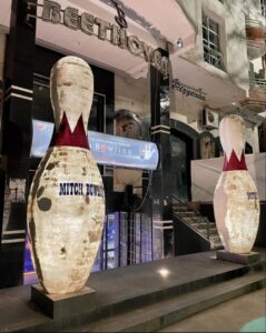 Night view of the entrance to Mitch Bowling Ifrane, featuring two large glowing bowling pin statues and the "Beethoven" signage on Boulevard Massira.