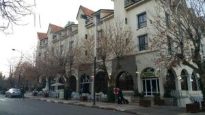 The exterior facade of Hotel Le Chamonix in Ifrane, Morocco, featuring traditional alpine architecture and an outdoor street cafe terrace.